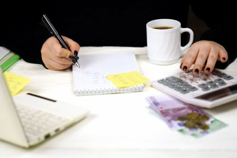 Vrouw schrijft op kladblok op bureau